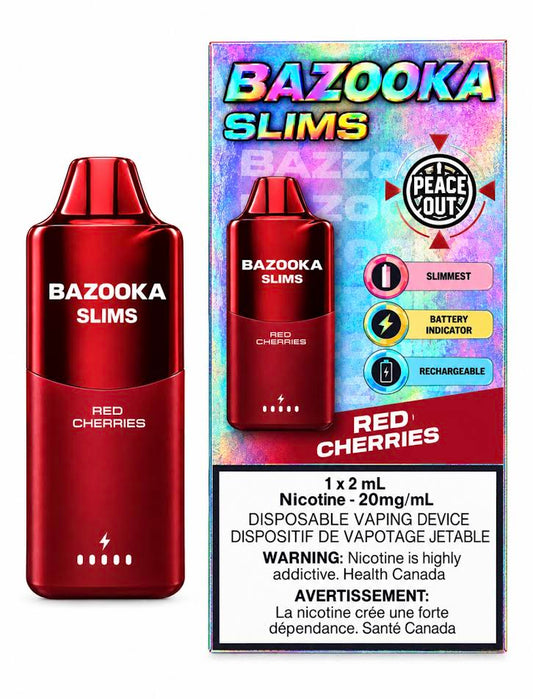 A blue Bazooka Slims disposable vaping device stands next to its retail box on a clean white background. The packaging is blue and white with 'BAZOOKA SLIMS' and 'RED CHERRIES' printed on it, plus a Peace Out badge and a nicotine warning label.